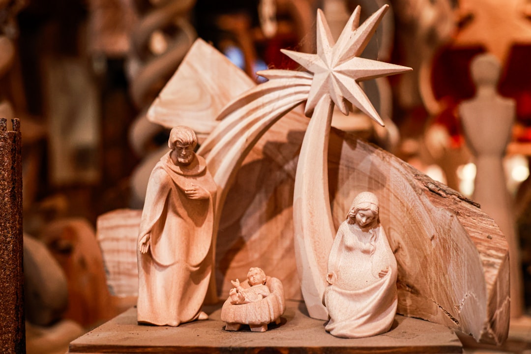 A wooden nativity scene featuring figures of Mary, Joseph, and baby Jesus in a manger, with a large star above them and a rustic background.