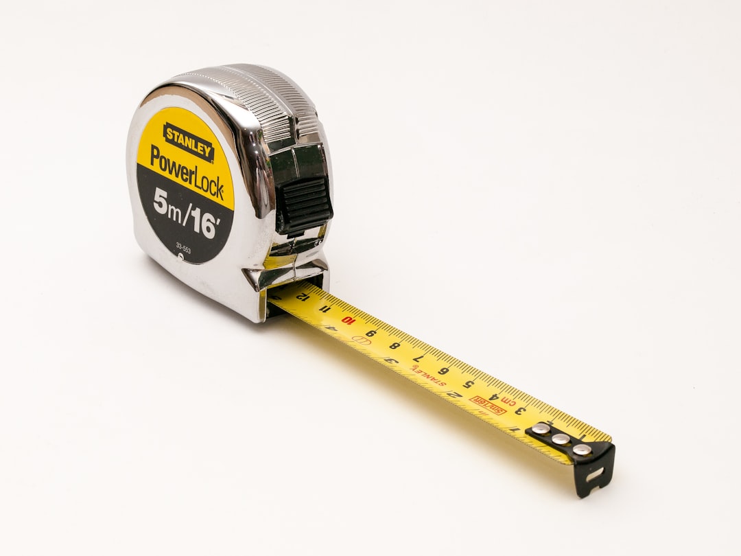 A Stanley PowerLock tape measure with a yellow measuring tape extended, showing 5 meters or 16 feet on the label, placed on a plain white background.